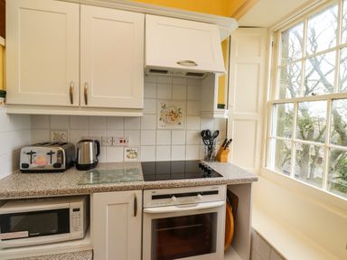 A kitchen countertop with toaster kettle stove oven microwave and utensils by a large window at Glebe House Bamburgh