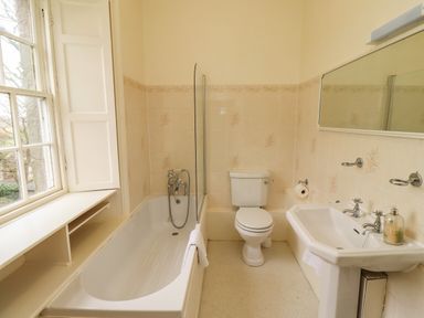 A bathroom with a bathtub sink toilet and a window at Glebe House in Bamburgh