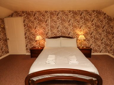 A bedroom with a double bed and two bedside tables with lamps at Glebe House in Bamburgh