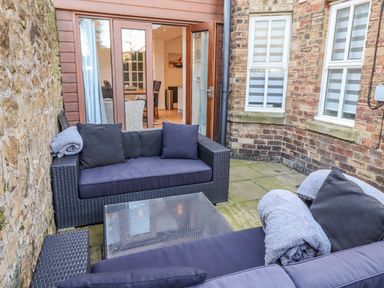 An outdoor patio with a seating area and a glass door at Alnbank in Alnmouth
