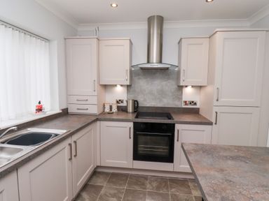 A kitchen with cabinets a sink an oven and a kettle at Bay View in Amble
