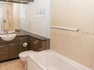 A bathroom with a bathtub shower toilet sink wooden cabinets and a large mirror at Bay View in Amble