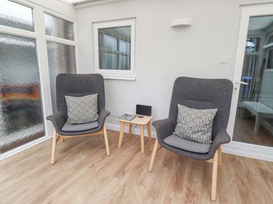 A seating area with two gray armchairs and a small wooden table between them at Bedwine Cottage in Beadnell