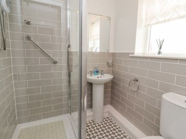 A bathroom with a shower enclosure sink and toilet at Bedwine Cottage in Beadnell