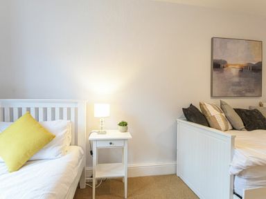 A bedroom with two beds a bedside table with a lamp and plant and a painting on the wall at Bellshill Cottage in Belford