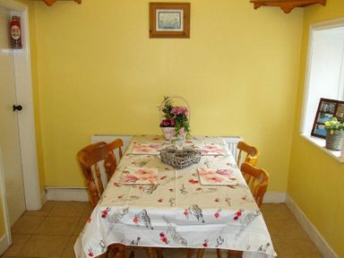 A dining area with a table covered by a patterned cloth and four wooden chairs at Briar Cottage in Town Yetholm and Kirk Yetholm