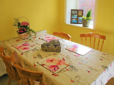 A dining area with a table covered in a floral tablecloth and wooden chairs at Briar Cottage in Town Yetholm and Kirk Yetholm
