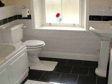 A bathroom with a toilet sink bathtub and a window with a flower on the sill at Briar Cottage in Town Yetholm and Kirk Yetholm