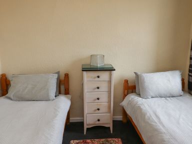 A bedroom with two single beds separated by a small chest of drawers at Budle Bay Cottage in Bamburgh