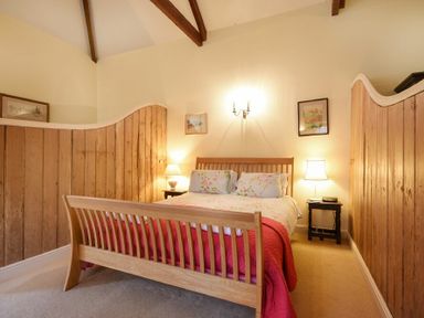 A bedroom with a wooden bed and nightstands with lamps at Craster Tower Coach House in Craster
