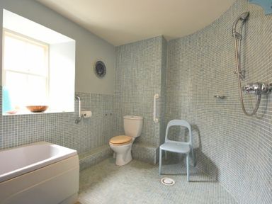 A bathroom with a bathtub toilet shower and chair at Craster Tower Coach House in Craster