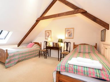 A bedroom with two single beds a wooden desk two chairs and a skylight at Craster Tower Coach House in Craster