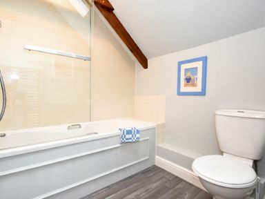 A bathroom with a bathtub a toilet and a framed picture on the wall at Craster Tower Coach House in Craster