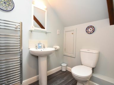 A bathroom with a pedestal sink mirror toilet and heated towel rail at Craster Tower Coach House in Craster