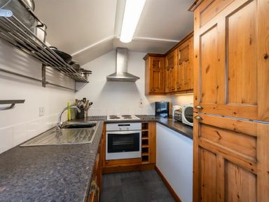 A kitchen with wooden cabinets a stove a sink and kitchen utensils at Fidra in Embleton