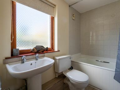 A bathroom with a sink toilet bathtub and a window with fish decoration at Fidra Embleton