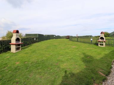 A garden with barbecues and a bench at Heather Cottages - Brent Goose in Bamburgh