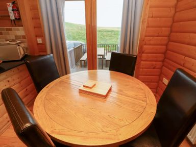 A dining area with a round table and chairs at Heather Cottages - Brown Owl in Bamburgh