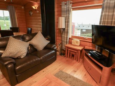 A living room with a sofa and television at Heather Cottages - Brown Owl, Bamburgh