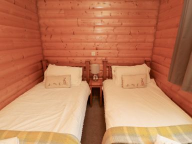 A bedroom with two single beds and a bedside table at Heather Cottages - Brown Owl in Bamburgh