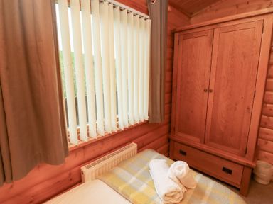 A bedroom with a bed and wardrobe at Heather Cottages - Brown Owl Bamburgh
