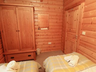 A bedroom with twin beds and wardrobe at Heather Cottages - Brown Owl in Bamburgh