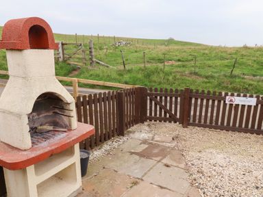 An outdoor area featuring a barbecue and a fence at Heather Cottages - Brown Owl Bamburgh
