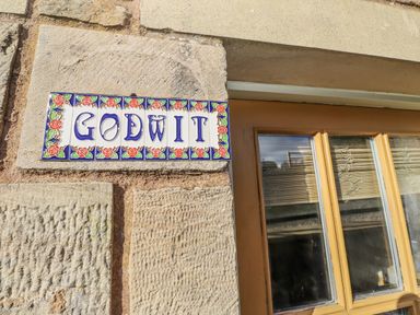 A sign labeled Godwit on a stone wall near a window at Heather Cottages - Godwit in Bamburgh
