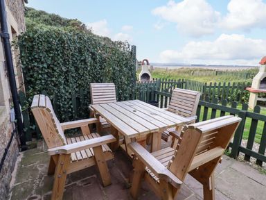 A table with chairs in an outdoor area at Heather Cottages - Grayling in Bamburgh