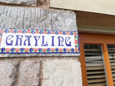 A sign with the word Grayling on a stone wall at Heather Cottages - Grayling Bamburgh