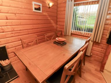 A dining room with a wooden table and six chairs at Heather Cottages - Grey Heron in Bamburgh