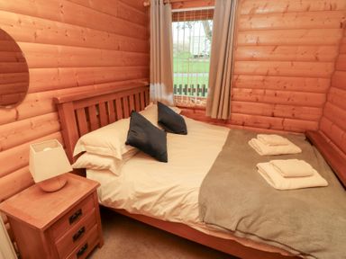 A bedroom with a double bed and window at Heather Cottages - Grey Heron in Bamburgh