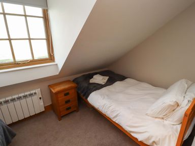 A bedroom with a bed and nightstand at Heather Cottages - Grey Seal, Bamburgh