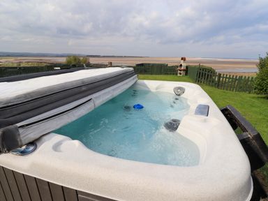 A hot tub with a cover in a garden at Heather Cottages - Grey Seal in Bamburgh