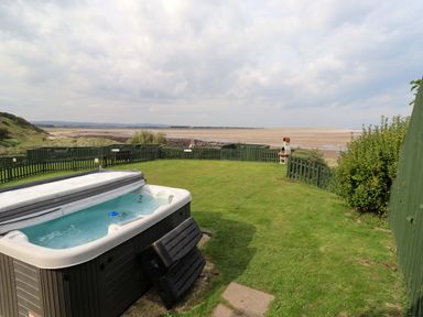 An outdoor space with a hot tub and sea view at Heather Cottages - Grey Seal in Bamburgh