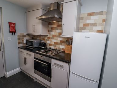 A kitchen with a stove and refrigerator at Heather Cottages - Plover in Bamburgh