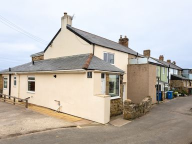 A row of houses on a street with a beige house at the corner marked number 1 at Island View in Amble
