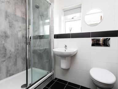 A bathroom with a shower enclosure sink toilet and round mirror at Island View in Amble