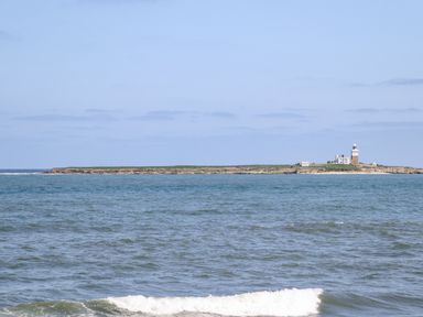 A view of an island with a lighthouse and buildings surrounded by the sea at Island View in Amble
