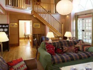 A living room with a wooden staircase two sofas and lamps by a window at Kirknowe in Jedburgh