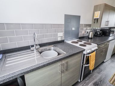 A kitchen with a sink and stove at Kittiwake Cottage, Budle Bay