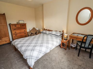 A bedroom with a bed, dresser, and table at Kittiwake Cottage, Budle Bay Bamburgh