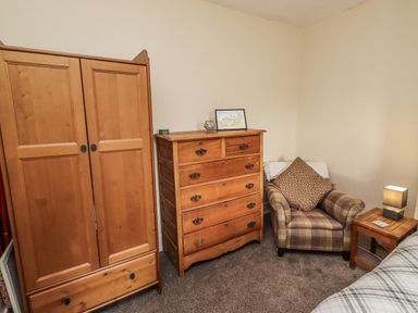 A bedroom with a wardrobe and chest of drawers at Kittiwake Cottage, Budle Bay