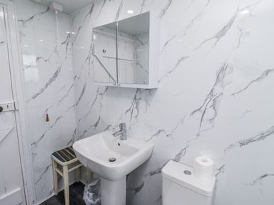 A bathroom with a sink, toilet and mirror at Kittiwake Cottage, Budle Bay