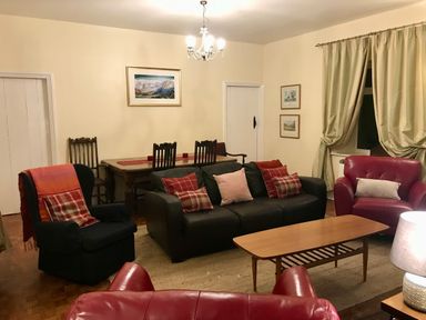 A living room with sofas chairs a wooden coffee table and a dining table with chairs at Leazes Cottage Rothbury