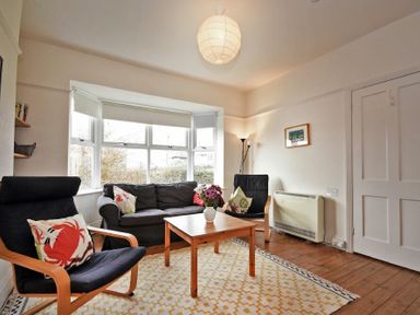 A living room with chairs sofa coffee table and a lamp at Melvin Cottage in Low Newton-By-The-Sea