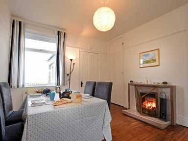 A dining room with a table set for a meal and a fireplace at Melvin Cottage in Low Newton-By-The-Sea