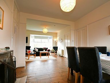 A living room with chairs a sofa and a coffee table next to a dining area with a table and chairs at Melvin Cottage in Low Newton-By-The-Sea