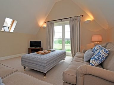 A living room with two sofas a large ottoman and a television at Sandpiper Bamburgh
