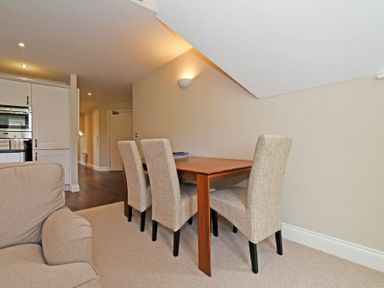 A dining area with a wooden table and four upholstered chairs next to a living space with a beige sofa at Sandpiper Bamburgh